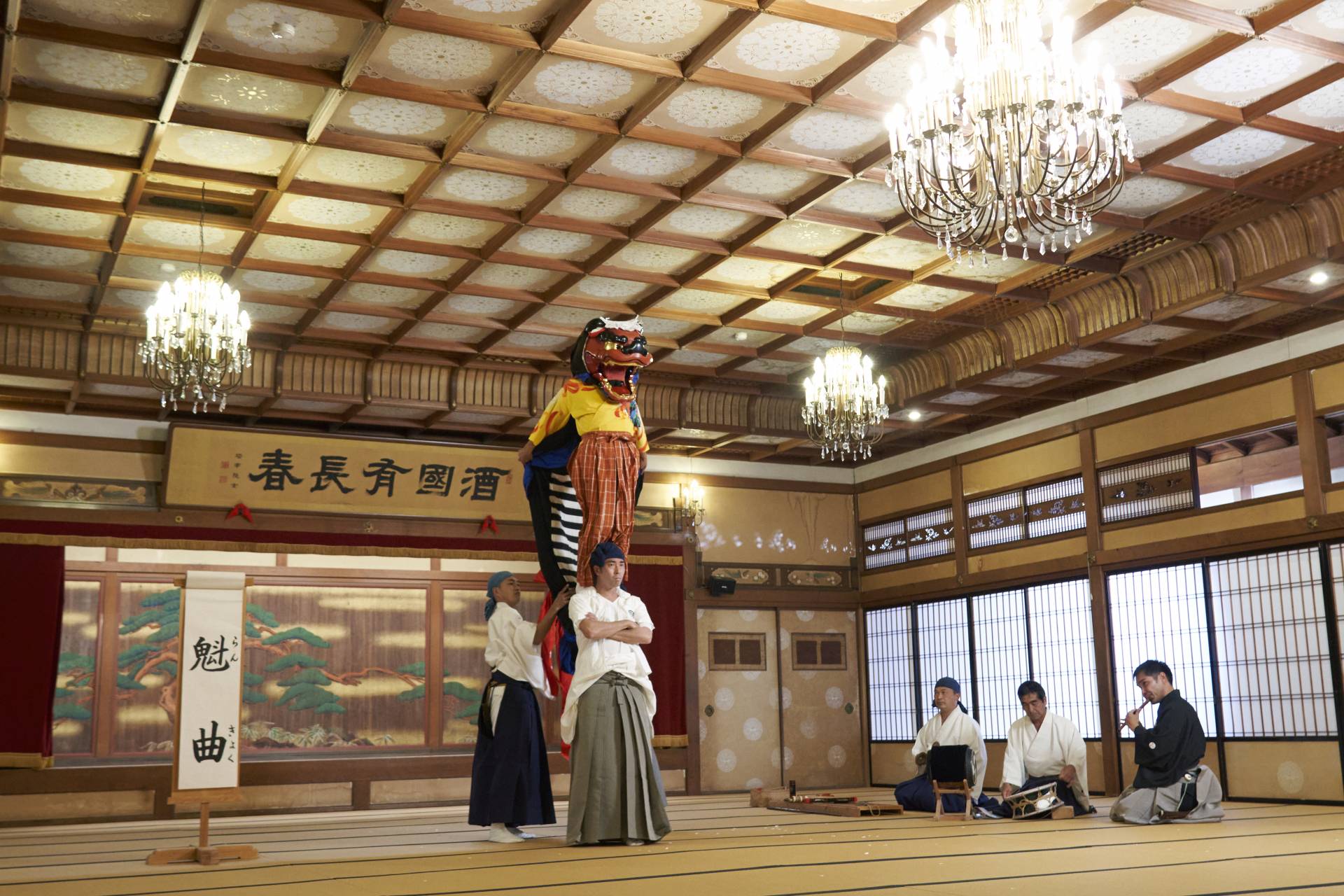 La musique des flûtes et des tambours résonne dans un espace noble, et la performance d'Okagura approche devant vous.