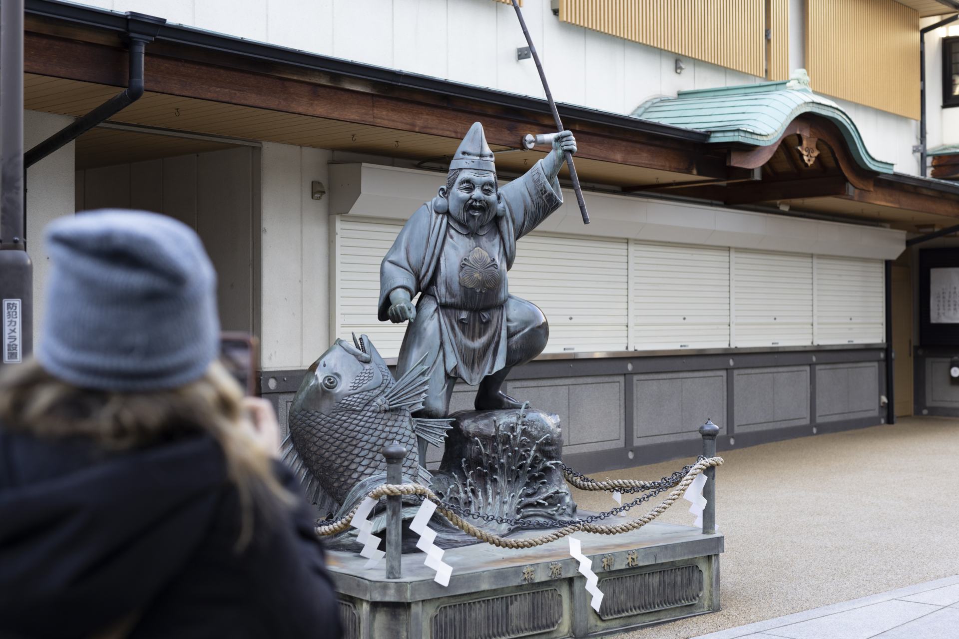 Amazed by the large statue of the deity, Ebisu, a symbol of wealth and prosperity for the merchants of Fuse.