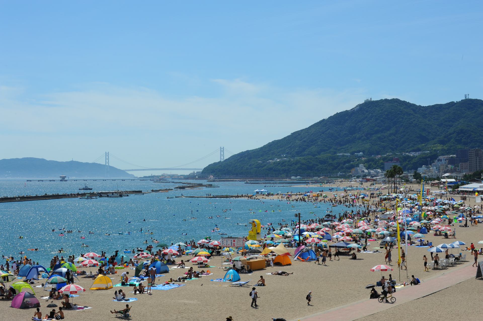 Akashi-Kaikyo Bridge can be seen by swimmers gathered at Suma Seaside Park in the summer.