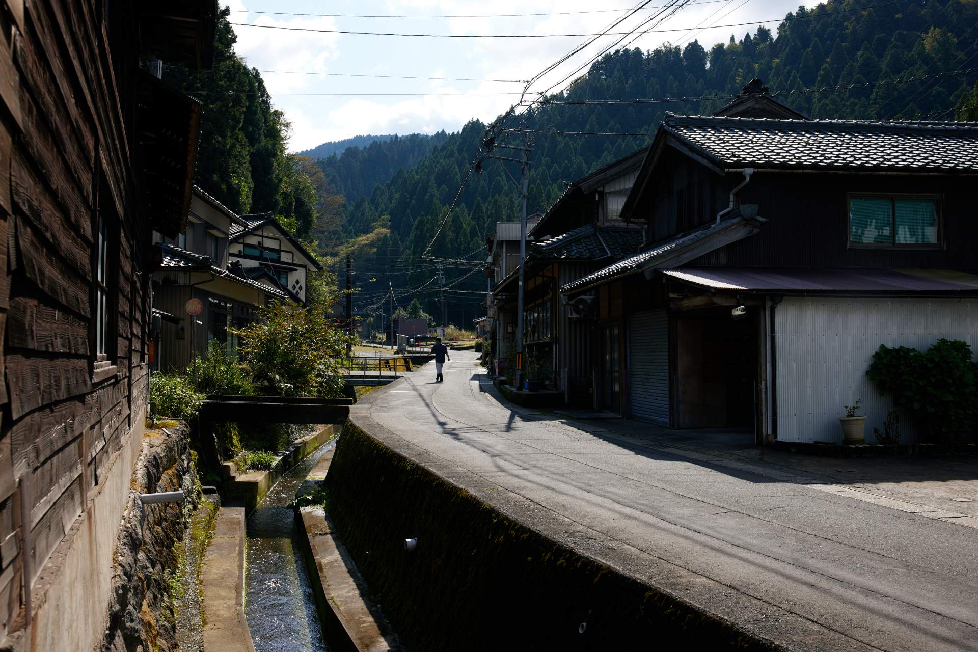 A babbling river slips through the quiet town as smoke rises from the paper mills steaming sanya paper and stripped bark from the mulberry plant. 