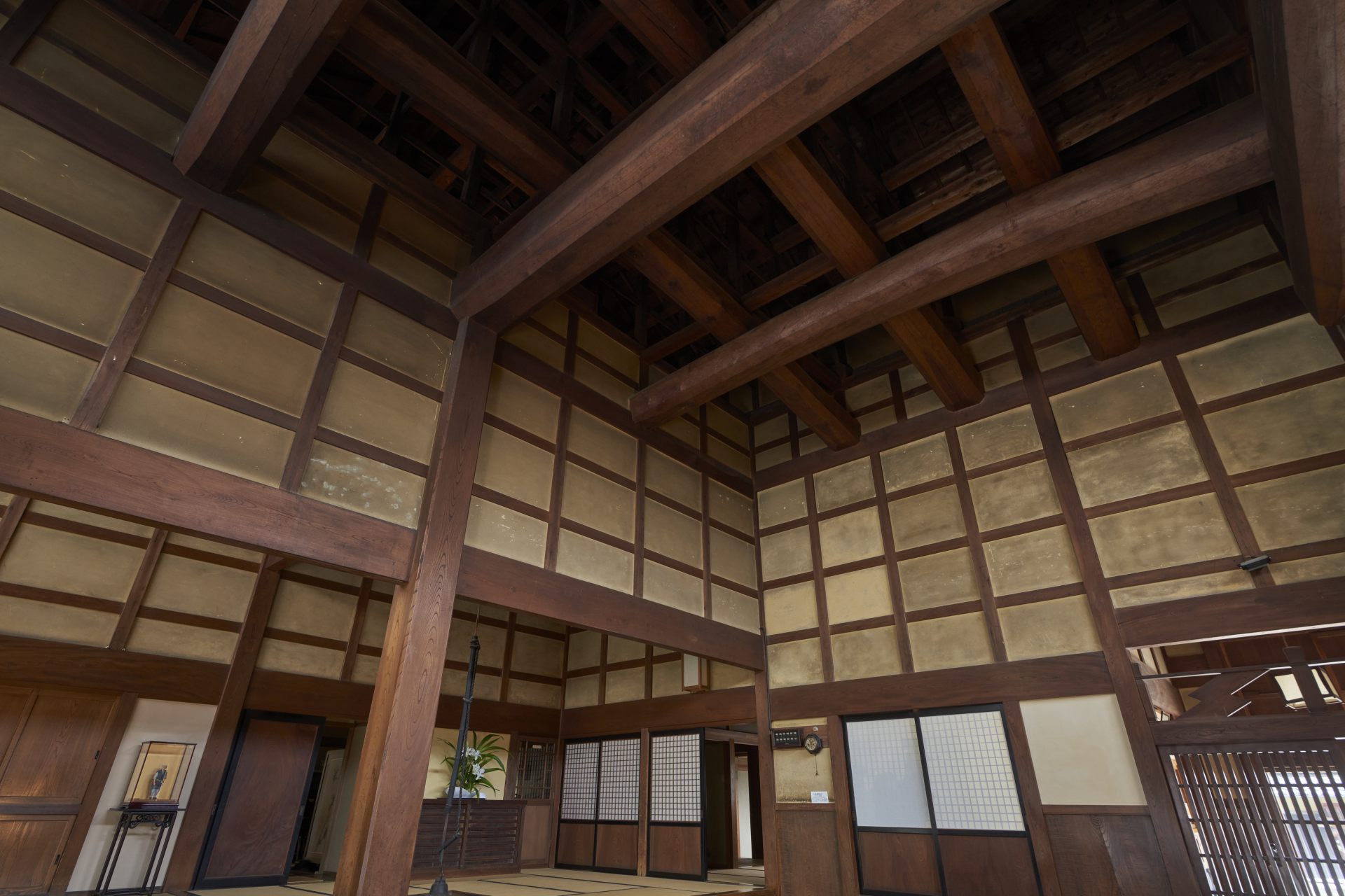 A dirt floor foyer and tall ceiling above set with oversized beams. Catch more glimpses of masterful, Japanese traditional architecture across the estate. 