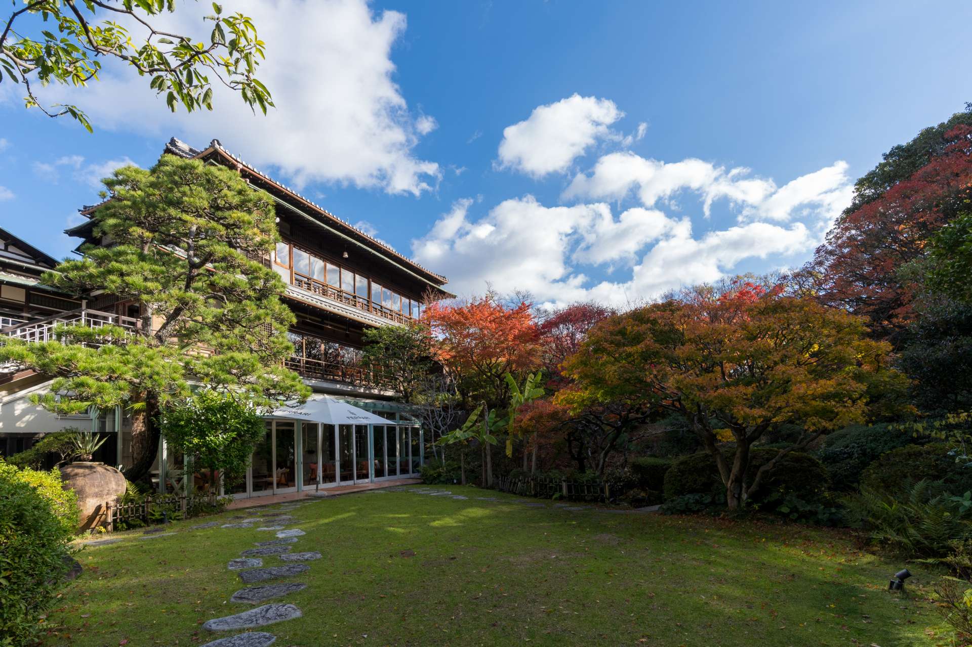 The expansive garden and luxurious villa are picturesque under a blue sky.