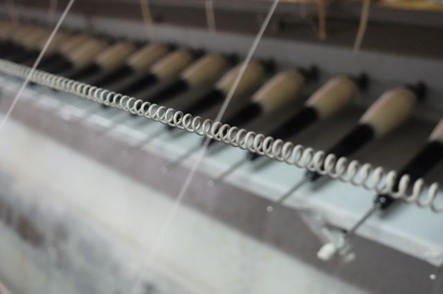 緯糸（よこいと）の準備工程「撚糸」です。緯糸に水を垂らしながら撚っていくことで、丹後ちりめん独特な凹凸「シボ」が生まれます。