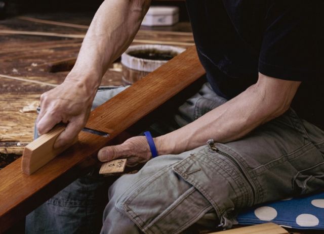 View of a craftsman at work (close-up of hands using a carpenter’s plane)
