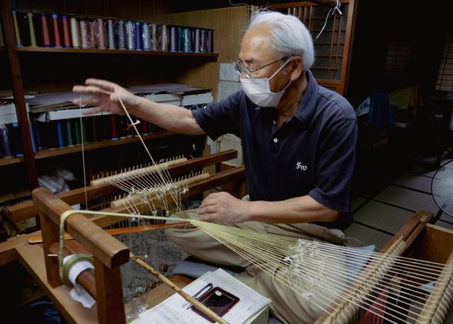 A craftsman working on a kumihimo loom