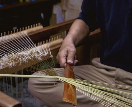 A craftsman working on a kumihimo loom (close-up of the hands)
