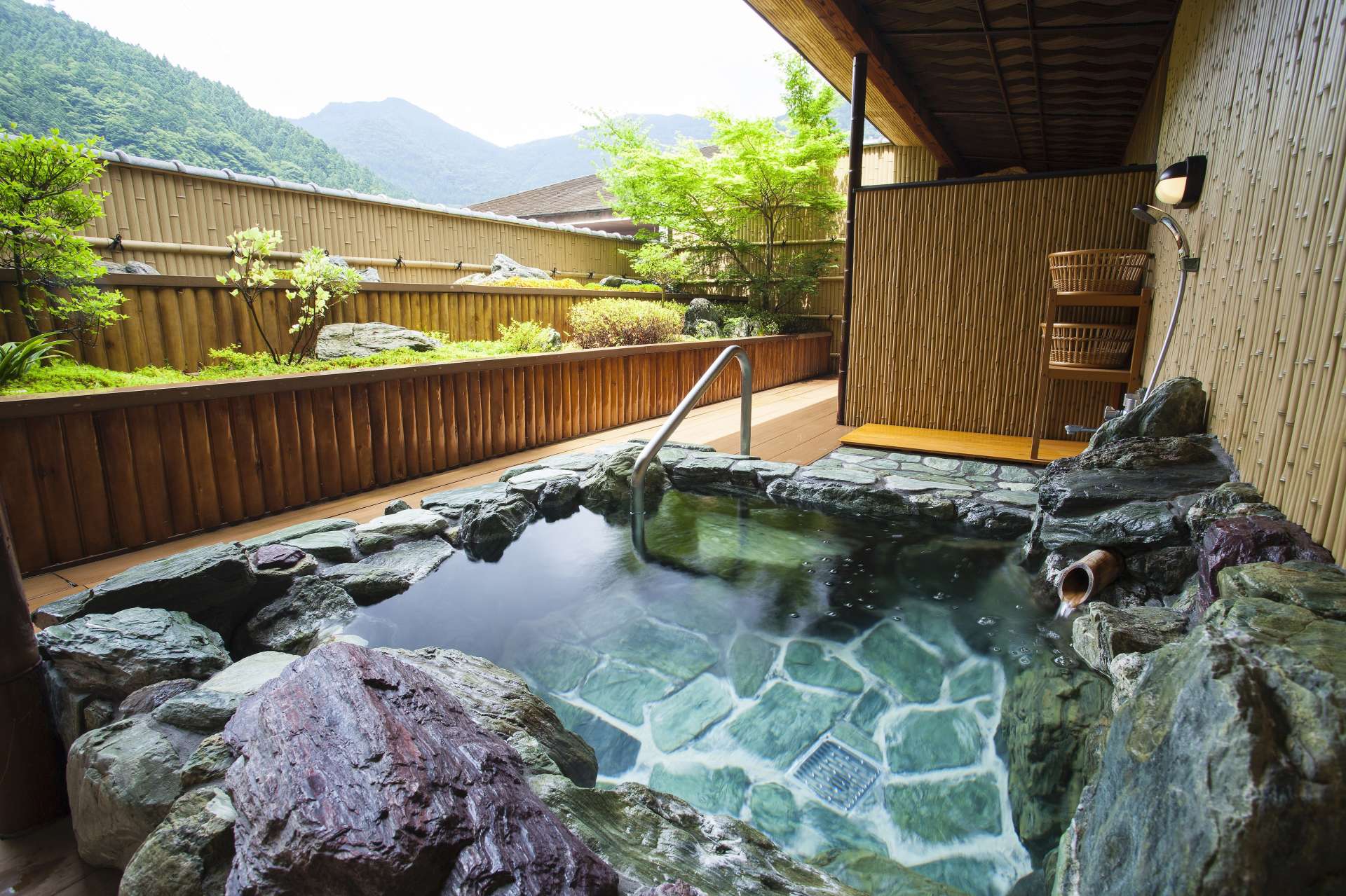 祖谷の青石造りの露天風呂から、日本庭園と山々が織りなす自然美を見上げて。